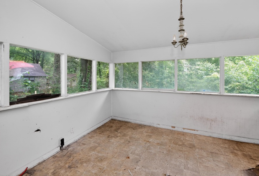 Sunroom with multiple large windows, a sloped ceiling, and a central chandelier fixture