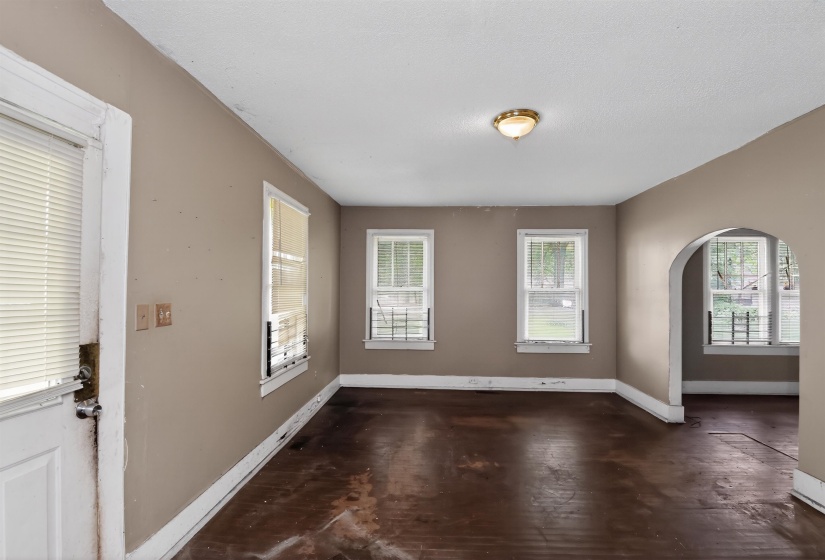 Interior room featuring wood-finish flooring, two windows with white trim, and a brass-finish ceiling light fixture
