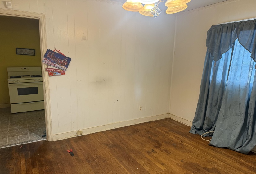 Hardwood-finish flooring extending into a spacious room with white paneled walls and a window
