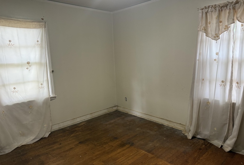 Room featuring wood-finish flooring, two window openings, and neutral wall tones