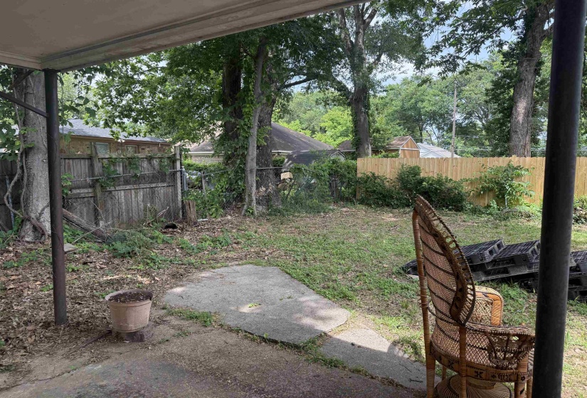 Spacious backyard featuring a concrete patio, mature trees, and a combination of wood and chain-link fencing