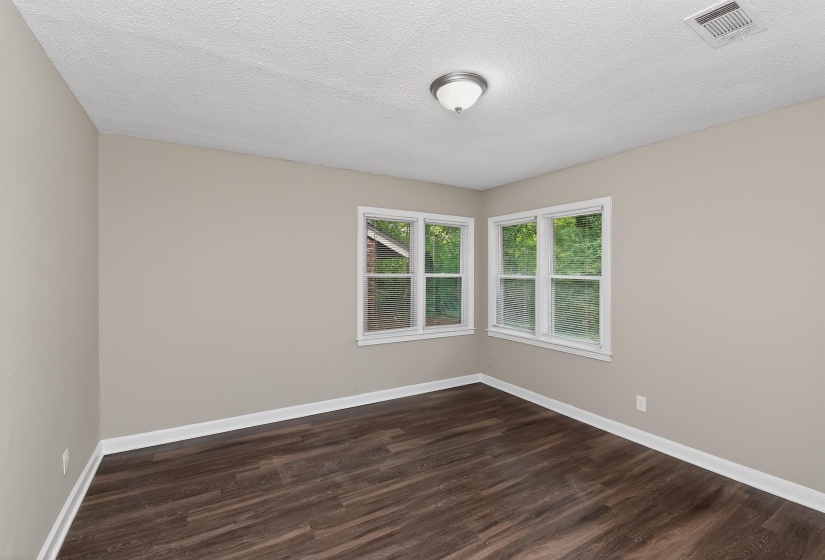 Room featuring wood-finish flooring, two large windows, neutral wall paint, white trim, and a ceiling-mounted light fixture