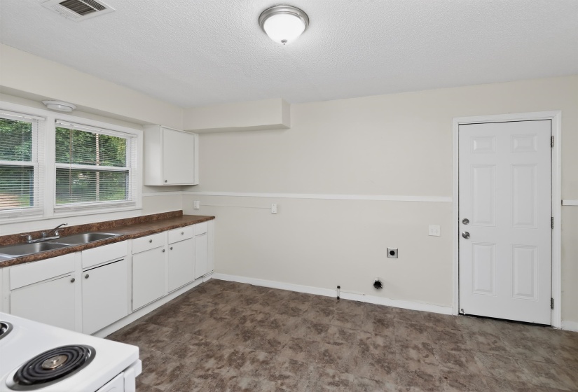 Functional kitchen space featuring white cabinetry, a double basin stainless steel sink, and a brown laminate countertop