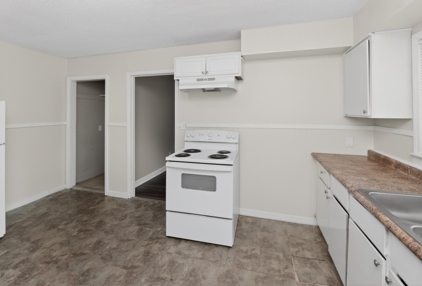 Kitchen featuring a white electric range, matching upper and lower cabinetry, a stainless steel sink, and a laminate countertop