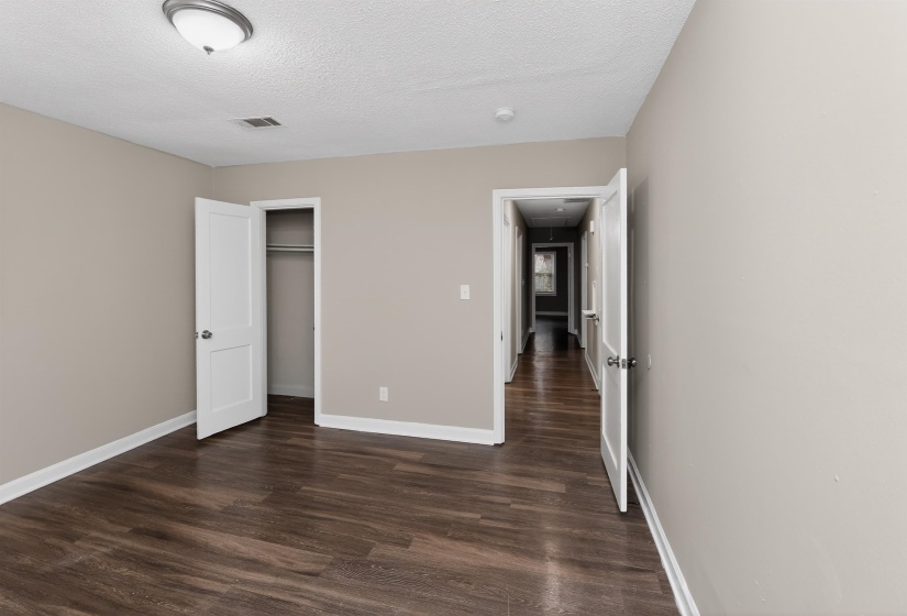 Neutral wall color, wood-finish flooring, white trim, and a semi-flush mount ceiling light