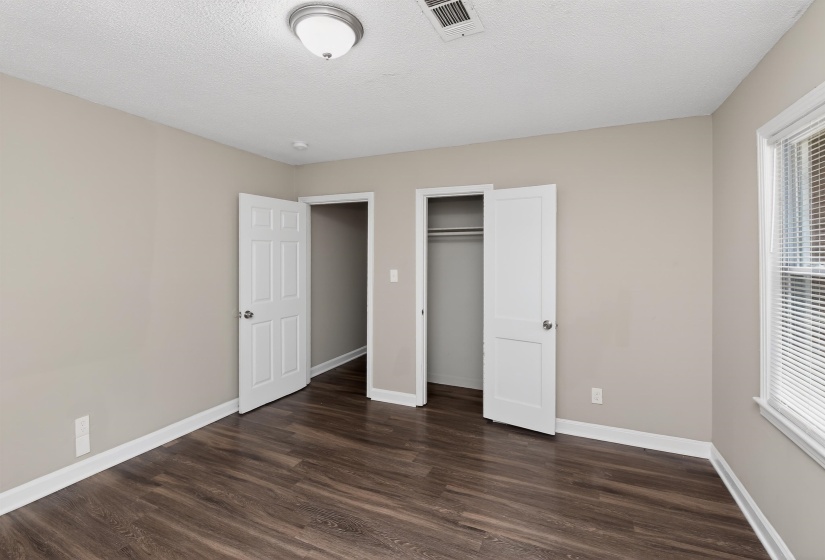 Spacious room featuring wood-finish flooring, light tan walls, and white trim