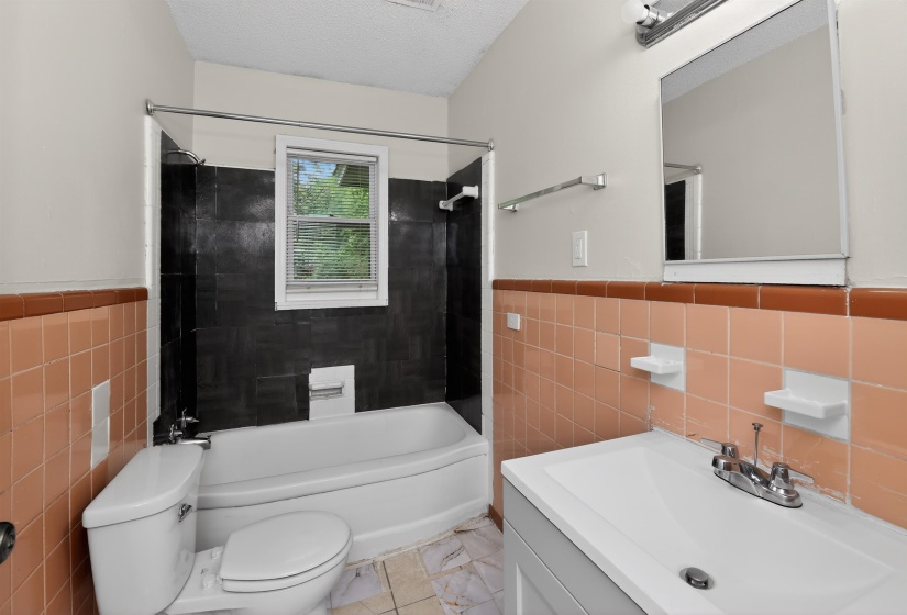 Bathroom featuring a white bathtub, a window with blinds, and white and brown wall tiling