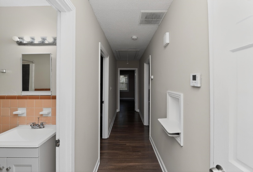 Hallway featuring wood-finish flooring, light grey wall paint, and white trim