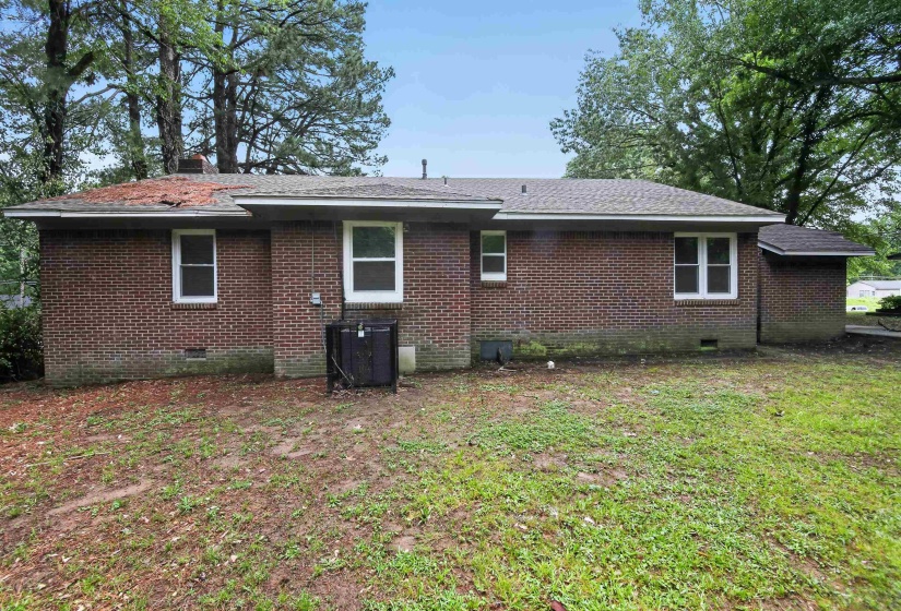 Brick exterior featuring multiple windows and a shingle roof