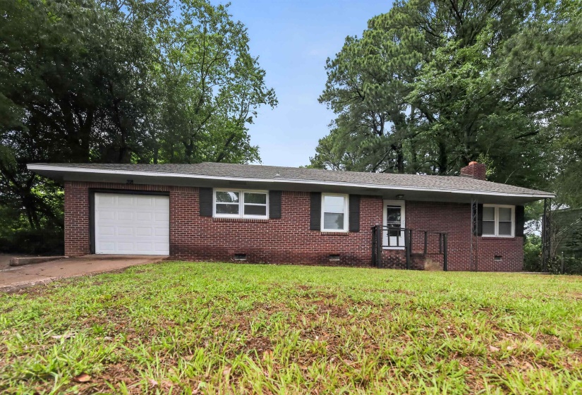 Brick exterior featuring a single-car garage and covered entry