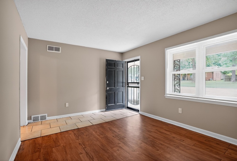 Entry area featuring wood-finish flooring extending into the main living space and a contrasting tile entry