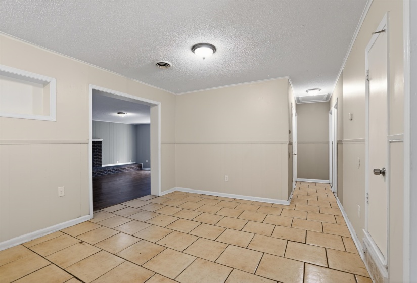 Expansive room featuring light-colored tile flooring, neutral wall tones, and recessed wall shelving