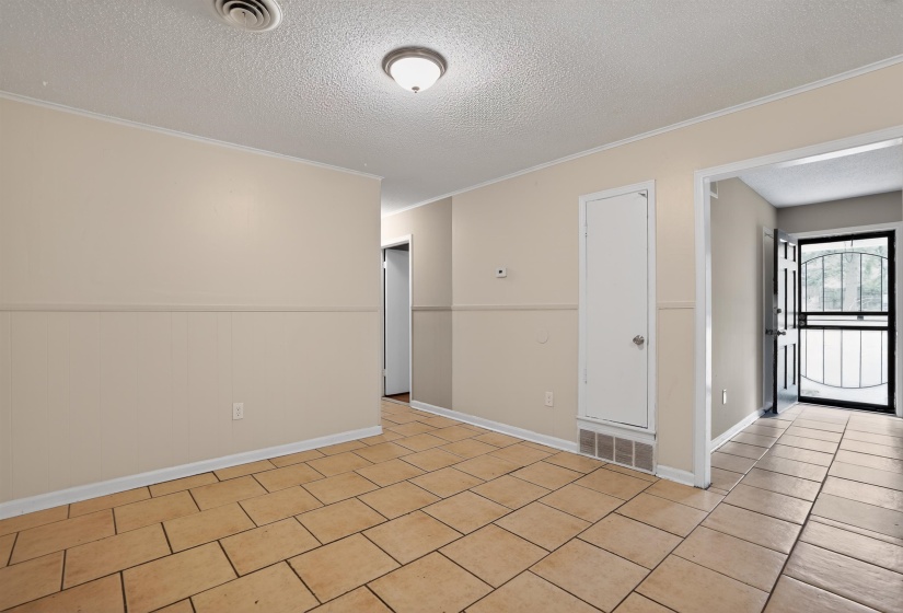 Light-colored tile flooring throughout, featuring a neutral wall palette, a ceiling-mounted light fixture, and a security screen door