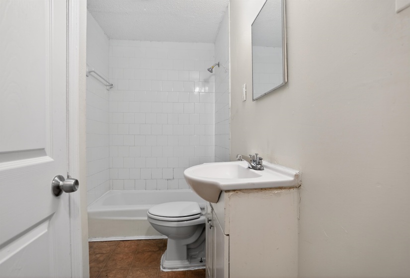 Full bathroom with white subway tile shower surround, a built-in bathtub, and a single vanity with a chrome faucet