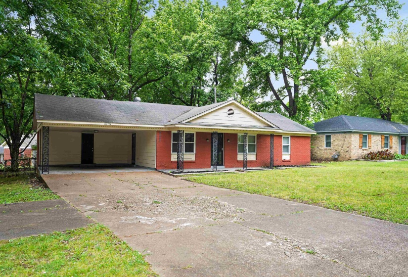 Brick facade residence with a covered carport featuring decorative wrought iron columns, a concrete driveway, and a front porch
