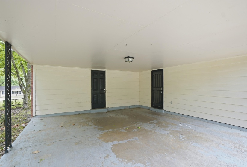 Carport featuring a concrete floor, two dark panel doors, horizontal siding, and an overhead light fixture
