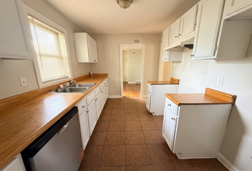 Kitchen featuring white cabinetry, wood-finish countertops, and a dual basin stainless steel sink with a window overhead