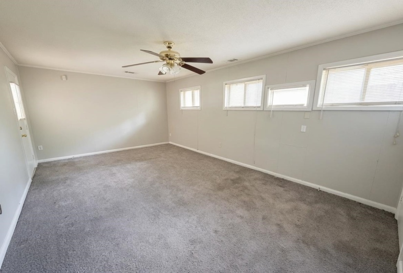 Spacious room with light gray walls and gray carpeting
