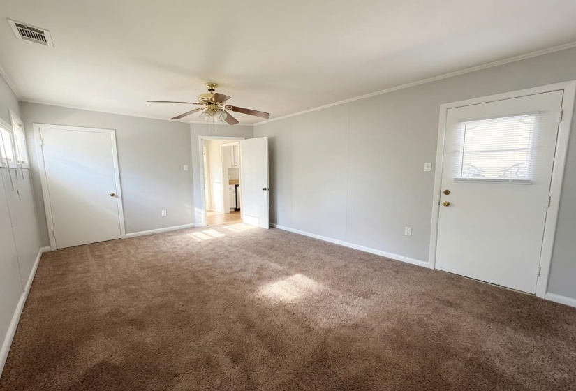 Spacious room featuring neutral paint, brown carpet, ceiling fan with light fixture, and white trim
