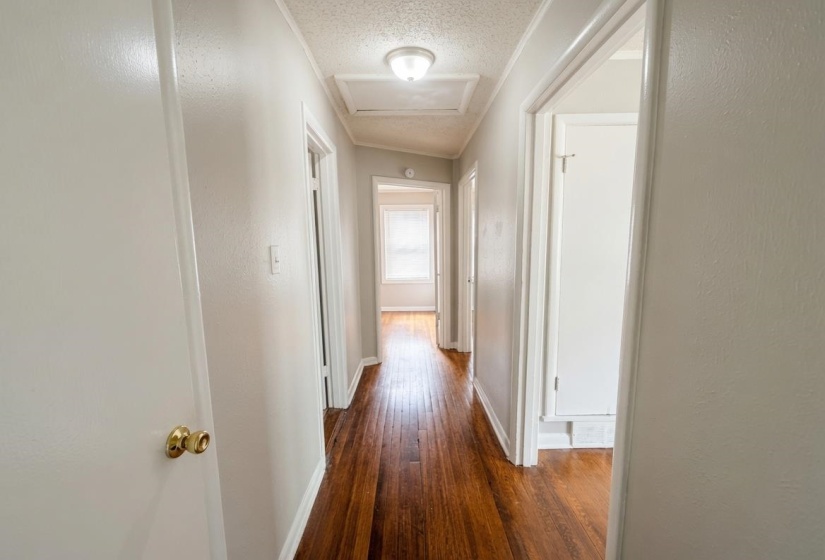 Hallway featuring wood-finish flooring, light grey painted walls, white trim, and flush mount ceiling light