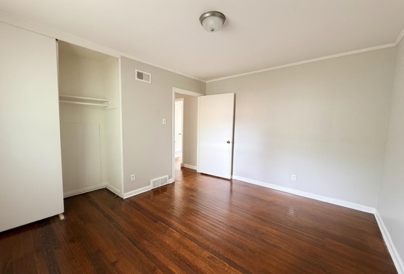 Hardwood flooring throughout, featuring a built-in closet with sliding doors and interior shelving