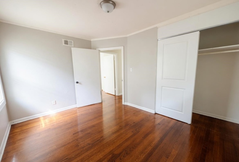 Hardwood flooring throughout, featuring a neutral wall palette, white trim, and a built-in closet with sliding doors