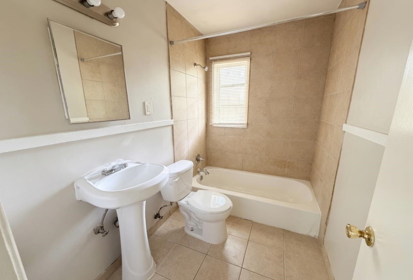 Bathroom featuring a pedestal sink, a toilet, and a bathtub with tile surround