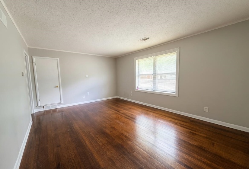 Spacious interior featuring rich wood-finish flooring, light gray wall paint, and white trim throughout