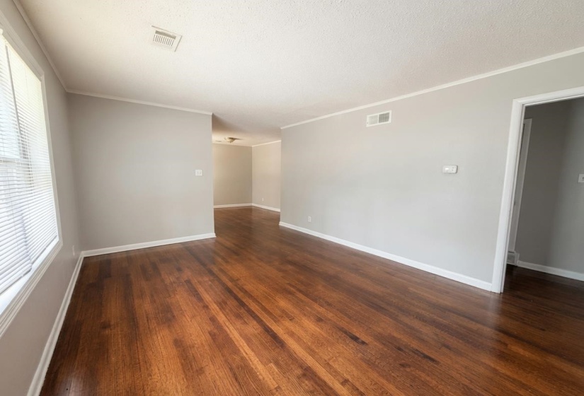 Living space featuring rich wood-finish flooring, light grey wall paint, and white trim work