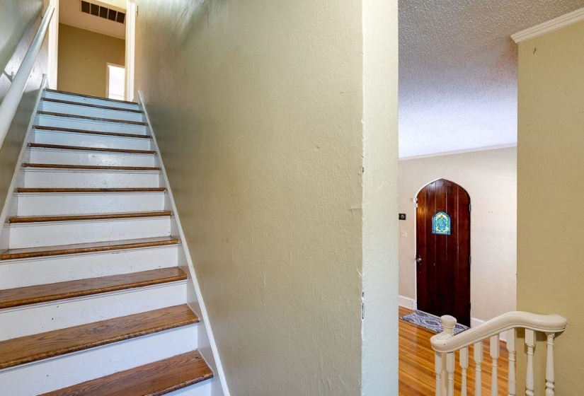 Hardwood treads and white risers define the staircase, complemented by light-toned wall finishes and a white handrail