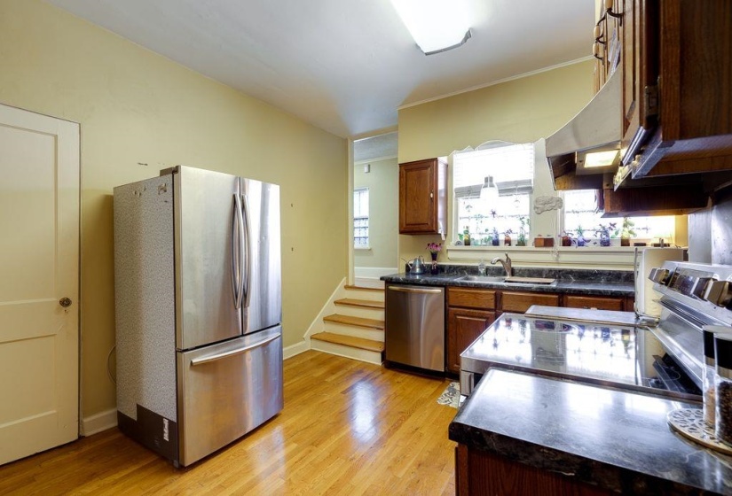 Kitchen featuring wood-finish flooring, dark stone-look countertops, and classic wood cabinetry