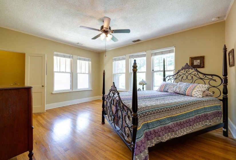 Spacious room featuring wood-finish flooring, light-toned walls, and multiple windows with white trim