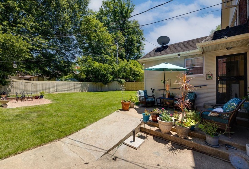 Expansive backyard featuring a manicured lawn, a privacy fence, and mature trees
