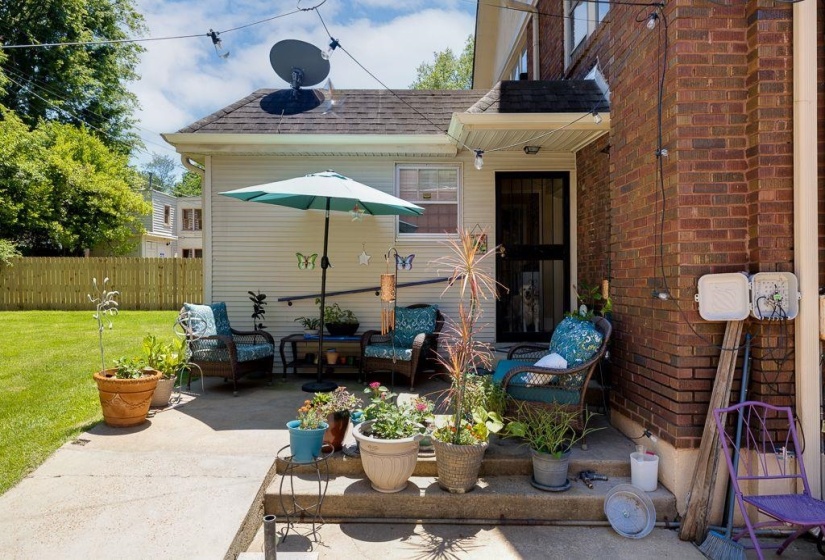Concrete patio featuring a privacy fence, manicured lawn, and brick exterior