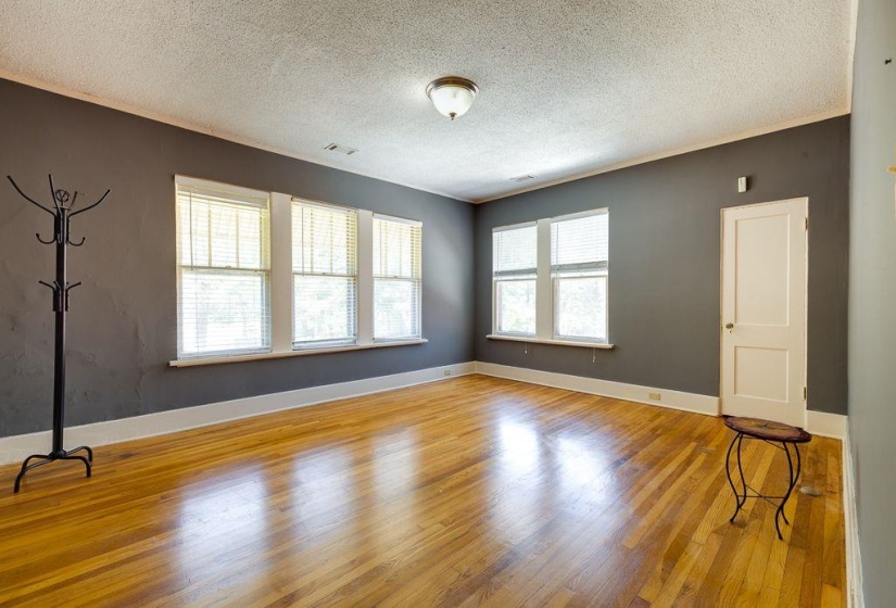 Room with wood-finish flooring, dark gray walls, and white trim