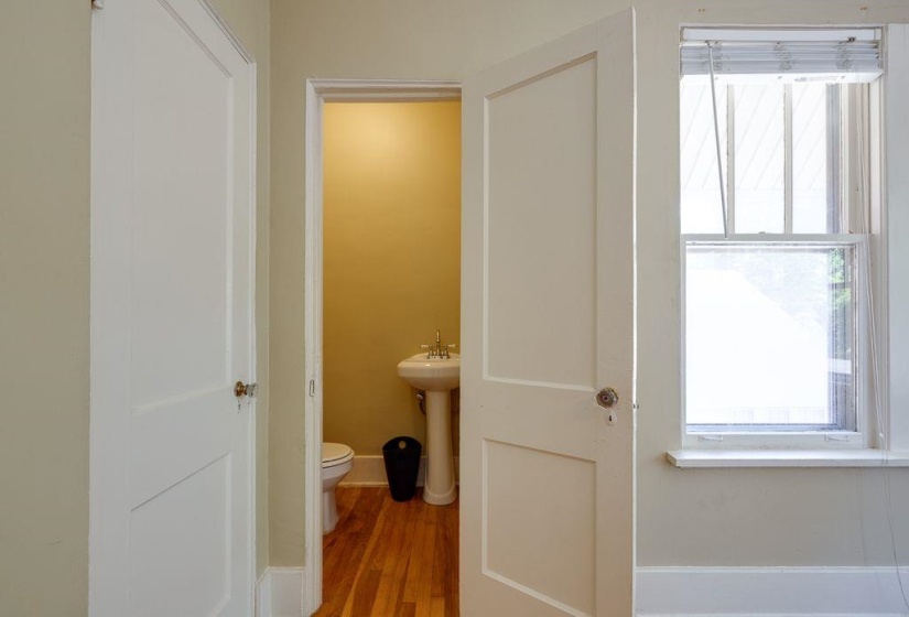 Powder room featuring a pedestal sink, toilet, and wood-finish flooring