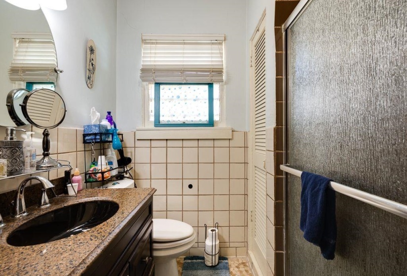 Bathroom featuring a dark wood-finish vanity with a black oval sink, a stone-finish countertop, and chrome fixtures