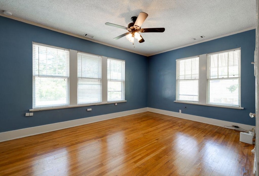 Room featuring wood-finish flooring, blue walls, white trim, and a multi-light ceiling fan