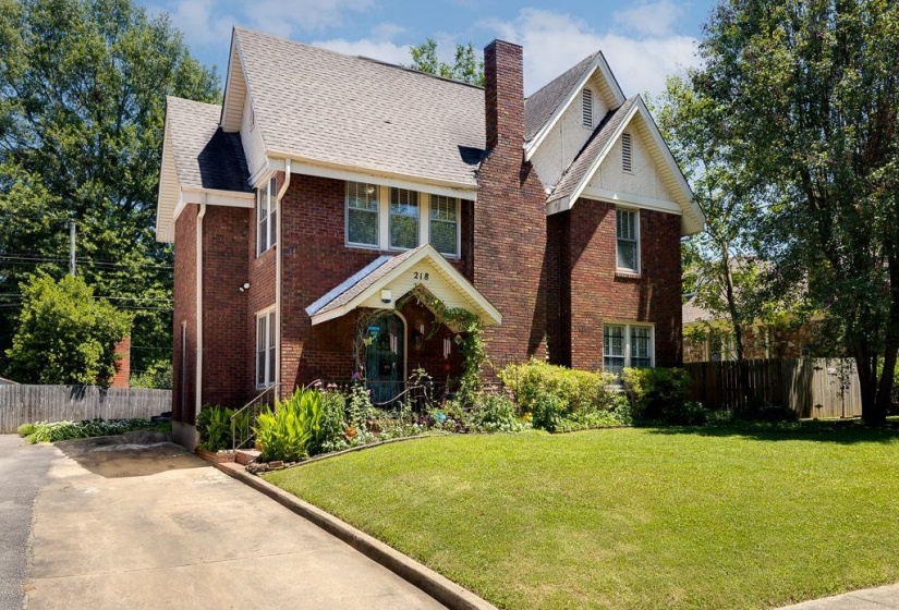 Traditional brick facade featuring a prominent front chimney, gabled rooflines, and a covered entry