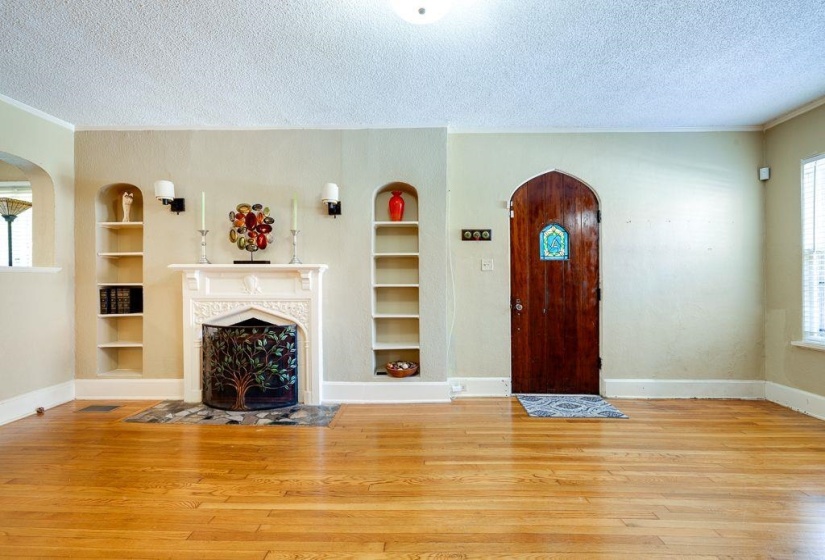 Hardwood flooring throughout the room features a decorative fireplace with a mantel