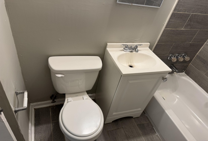 Bathroom featuring a white toilet, single-basin vanity with base cabinet, and an integrated bathtub