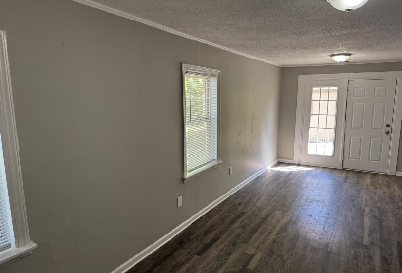 Spacious room featuring wood-finish flooring, neutral-toned walls, and white trim