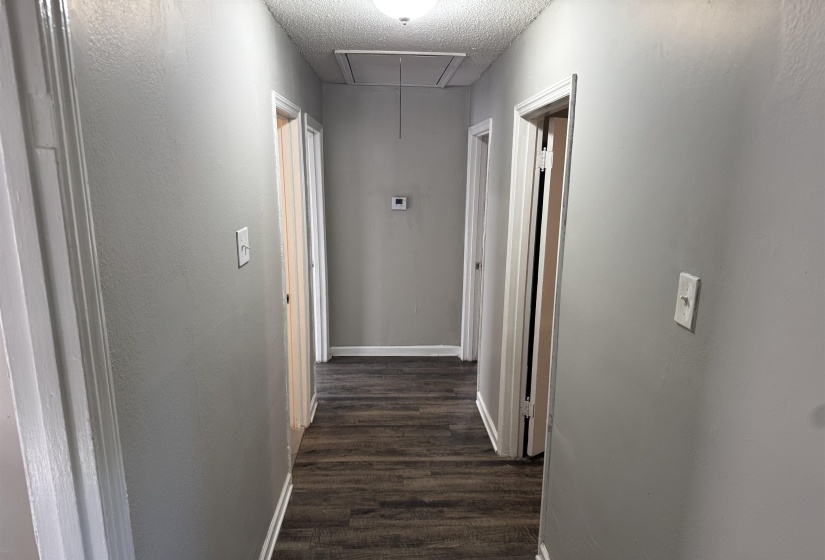 Hallway with wood-finish flooring, light gray walls, white trim, and recessed lighting