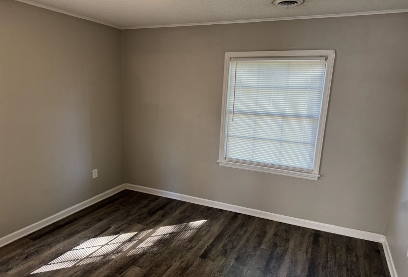 Room featuring a window with blinds, light gray wall paint, white trim, and dark wood-finish flooring