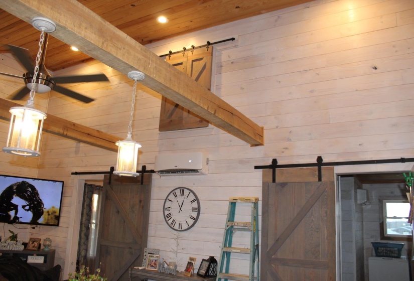 Detailed view of a barn door, wooden walls, a wood ceiling with exposed beams, and recessed lighting