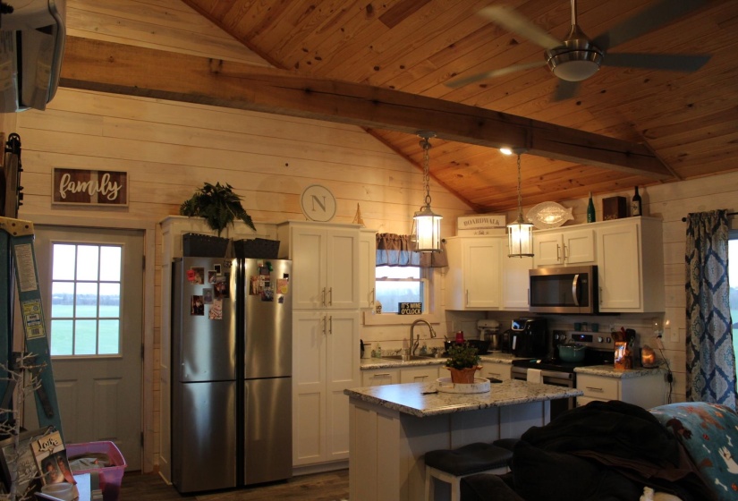 Kitchen featuring appliances with stainless steel finishes, wood ceiling, white cabinetry, ceiling fan, and wood walls