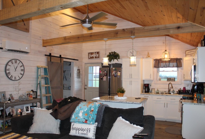 Kitchen with appliances with stainless steel finishes, a wall mounted air conditioner, wood walls, a barn door, and a ceiling fan