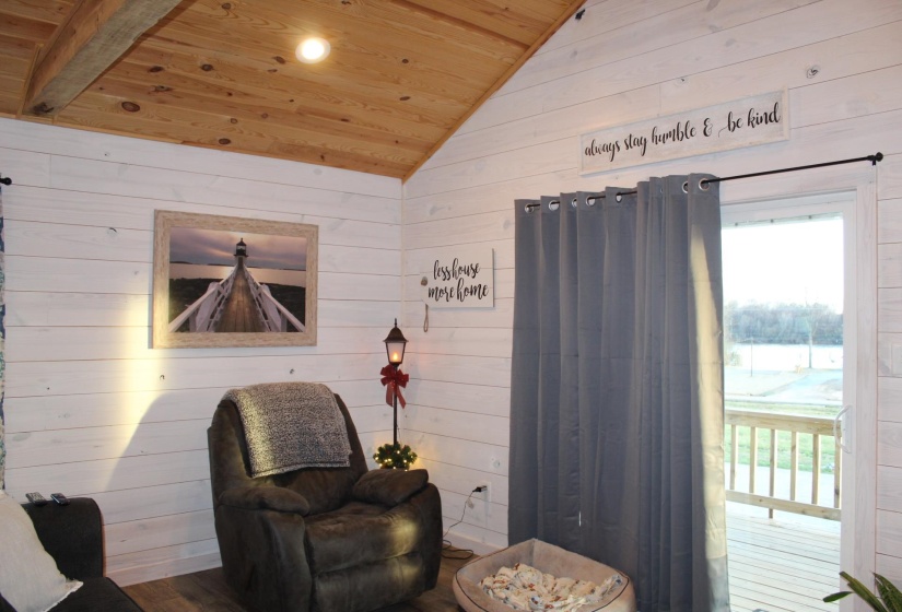 Living area with wood ceiling, vaulted ceiling, wooden walls, and plenty of natural light