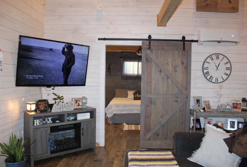 Living room featuring wooden walls, a barn door, and wood finished floors