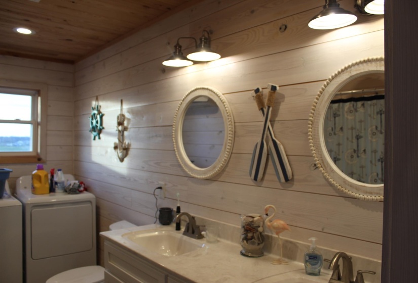 Bathroom with washer and clothes dryer, wood walls, wooden ceiling, double vanity, and recessed lighting
